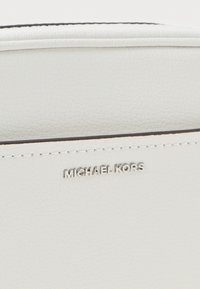 White textured leather bag with a silver "MICHAEL KORS" logo embossed on the front. Features clean lines and minimalistic design.