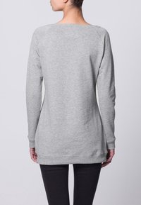 Sudadera gris con un corte relajado, escote redondo y mangas largas; cuenta con puños y bajo acanalados, fabricada con un tejido suave y texturizado.