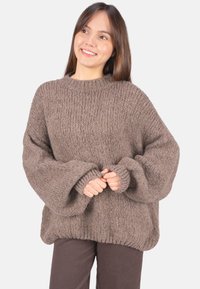 Brauner, grob gestrickter Pullover mit hohem Kragen und weiten Ärmeln, mit einem strukturierten Rippenmuster und lockerem Schnitt.