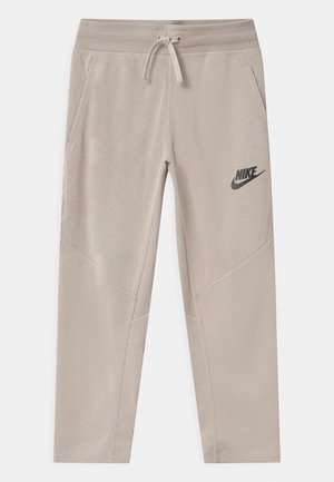 Beige Nike joggingbukser med snøre i taljen, to sidelommer og sort Nike-logo på venstre lår, vist fladt på hvid baggrund.