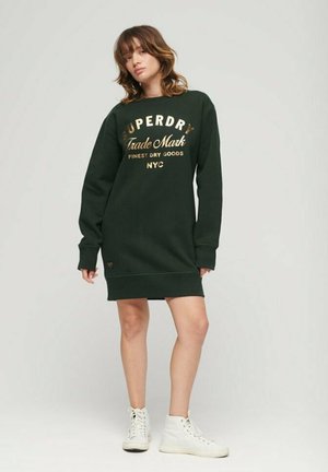 Robe-sweat verte avec un logo doré imprimé, des manches longues, des poignets côtelés et une coupe décontractée, assortie à des baskets montantes blanches.