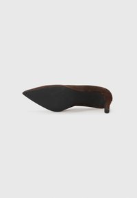 Brune semskede høyhælede sko med spiss tå og svart såle. Hælen er slank og omtrent 7,5 cm høy.