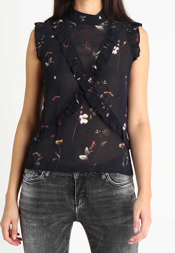 Black sheer top with floral patterns, ruffled accents along the shoulders and front, high neckline, paired with grey jeans.