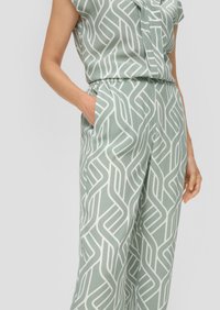 Lichtgroene stoffen set bestaande uit een shirt en bijpassende broek. Het ontwerp heeft een wit geometrisch patroon met een elastische tailleband en zakken.