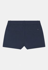 Pantaloni corti da donna blu navy con passanti per cintura, due tasche posteriori a fessura e un piccolo logo rettangolare sulla tasca destra.