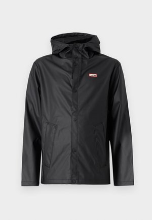 Must põrand ja veekindel vihmakeep, millel on kapuuts, nööbid, kaks esikotid ja logo sildiga, millel on punase ja valge detailid. Sile tekstuur.