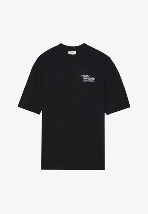 Zwarte katoenen t-shirt met korte mouwen, een ronde hals en witte tekst die "YEARS/UNFOLDED" op de linkerborst staat.