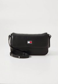 Must nahast üle õla kott, mis sulgub kaane kaudu, reguleeritav rihm ja esiküljel väike ristkülikukujuline logo punase, valge ja sinise värviga.