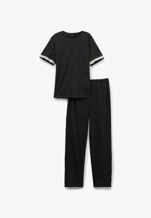 Conjunto de top de manga corta negro y pantalones largos con pequeños lunares blancos, que cuenta con un ribete plateado en los puños de las mangas.