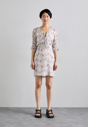 Leichtes Kleid mit Blumenmuster, mit V-Ausschnitt, 3/4-Ärmeln und tailliertem Schnitt. Kombiniert mit schwarzen Plateau-Sandalen.