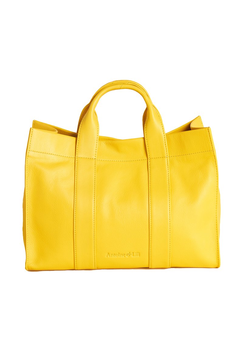 Gelbe Leder-Tote-Bag mit zwei oberen Tragegriffen, rechteckiger Form, glatter Textur, sichtbaren Nähten und prägtem Logo auf der Vorderseite.