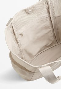 Beige hálós vászontáska belső része cipzáras zsebbel. Puha szövetbélés, két fogantyú és tágas kialakítás különböző tárgyak számára.