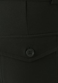Black fabric shorts featuring a front pocket with a flap and a black four-hole button closure. Smooth texture with clean stitching details.