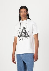 White cotton t-shirt featuring a black geometric graphic design on the front. Short sleeves, crew neckline, and relaxed fit.