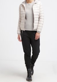 Helles graues Pufferjacke mit Kapuze, strukturierter grauer Pullover, schwarze Jogginghose und schwarze Schnürstiefel. Minimalistisches Design, bequeme Passform.