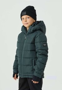 Ciemnozielona pikowana kurtka z kapturem, zamkiem błyskawicznym i bocznymi kieszeniami. Posiada czarne elastyczne mankiety oraz naszywkę z logo na rękawie.