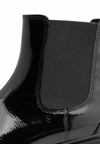 Botte Chelsea en cuir verni noir avec panneau latéral en élastique, surface lisse, bout rond et détail de couture discret.