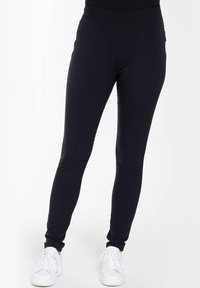 Zwarte, elastische leggings met een hoge tailleband, taps toelopende broekspijpen, gemaakt van een soepele stof. Geen zichtbare patronen of hardware accentueringen.