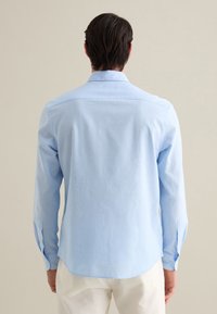 Lichtblauw langemouwen shirt van een zachte stof, met een rugpand en knoopmanchetten, een gebogen zoom en een soepele textuur.