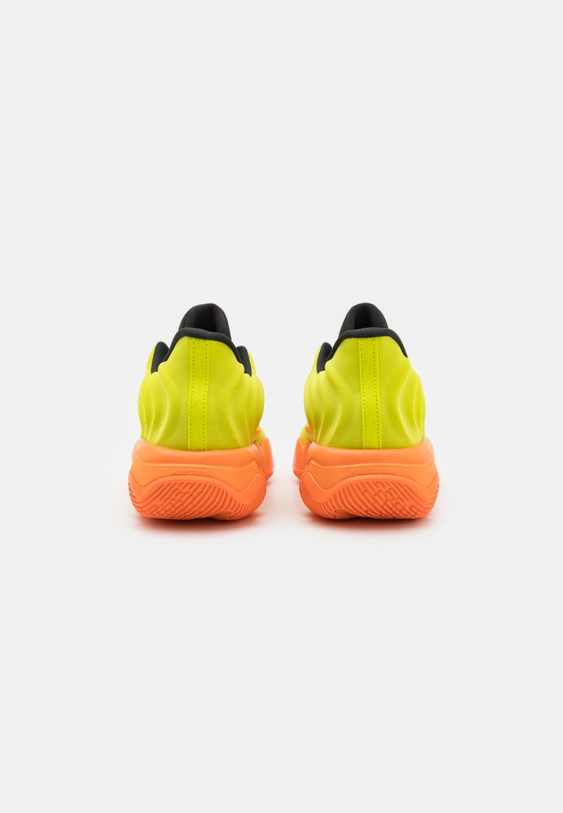 Sneakers atletici giallo neon con una suola arancione texturizzata, caratterizzati da una fodera nera e un design minimalista. La vista posteriore mette in risalto le linee morbide.