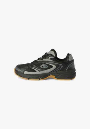 Zapatilla deportiva negra y gris con paneles de malla, diseño con cordones y suela color goma, mostrada desde el lado exterior.