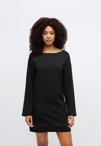 Črna obleka z dolgimi rokavi, okroglim izrezom in subtilnim detajlom na robu. Izdelana iz mehke tkanine, ima sproščen kroj in gladko teksturo.