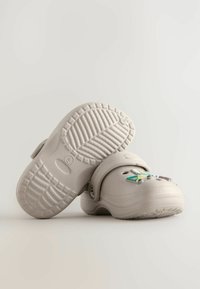 Zoccoli grigio chiaro con superficie texture, caratterizzati da un design stampato e una cinturino posteriore regolabile, decorati con accenti colorati.