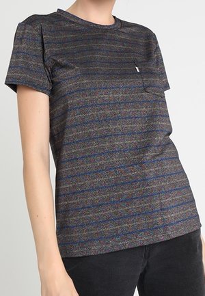 Person iført en mørkegrå kortærmet T-shirt med diskrete vandrette striber og brystlomme, kombineret med sorte bukser, på lys baggrund.