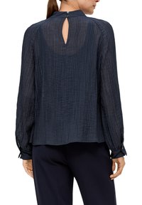 Marineblauwe blouse met lange mouwen van textuurstof, met een subtiel verticaal streepjespatroon, knoopsluiting aan de achterkant en aansluitende manchetten.