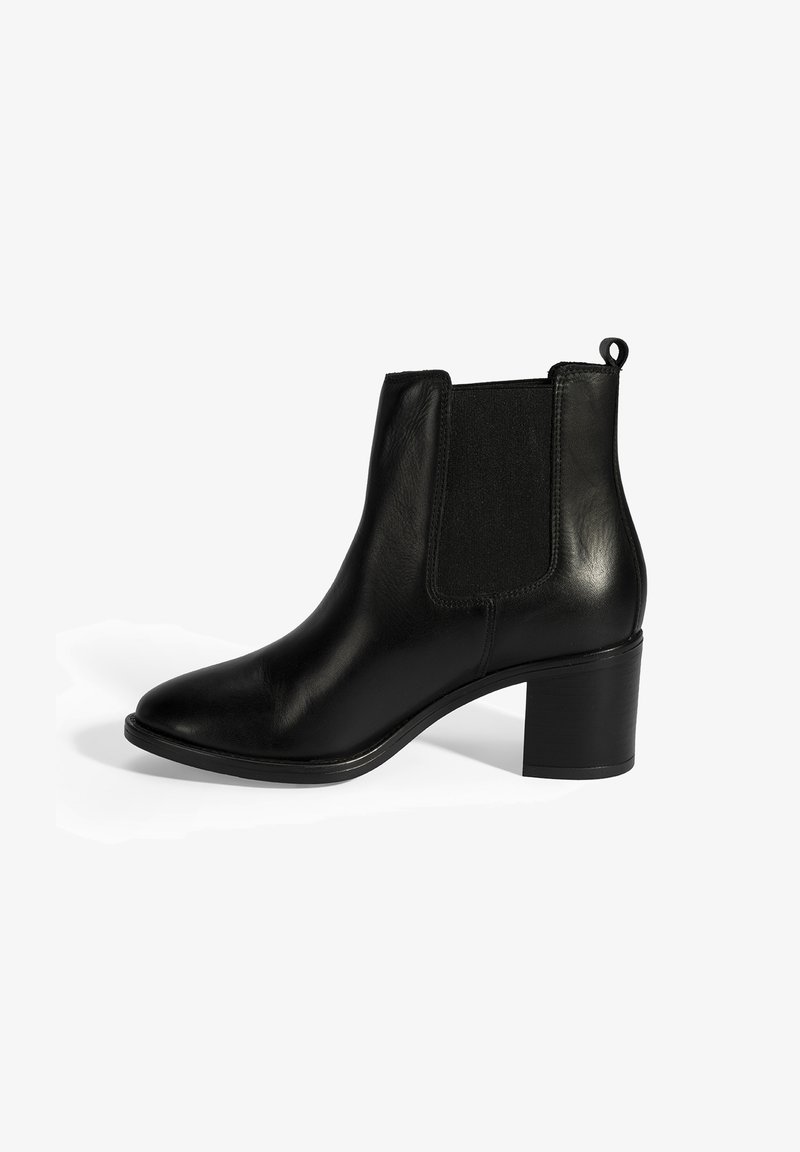 Bottines en cuir noir, avec des panneaux élastiques sur les côtés, bout pointu et talon bloc. Elles sont dotées d'une languette à l'arrière pour un enfilage facile.