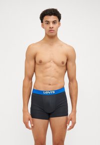 Shorts de boxeur noirs avec une ceinture bleue arborant le logo "Levi's". Le matériau semble lisse ; la coupe est ajustée et épousant bien les formes.