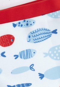 Tela estampada adornada con varios peces en tonos rojos y azules, con un borde texturizado rojo a lo largo del borde superior.