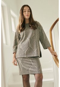 Conjunto de punto gris que incluye una blusa suelta con patrones negros ondulados y una falda ajustada. Textura suave con mangas tres cuartos.