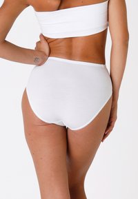 Mutande bianche in cotone a vita alta con texture liscia, elastico in vita, bordi ondulati e senza motivi o hardware visibili.