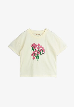 Camiseta de algodón amarilla de manga corta con bordado floral en rosa brillante y hojas verdes, y un cuello redondeado. Nombre de la marca impreso debajo de las flores.