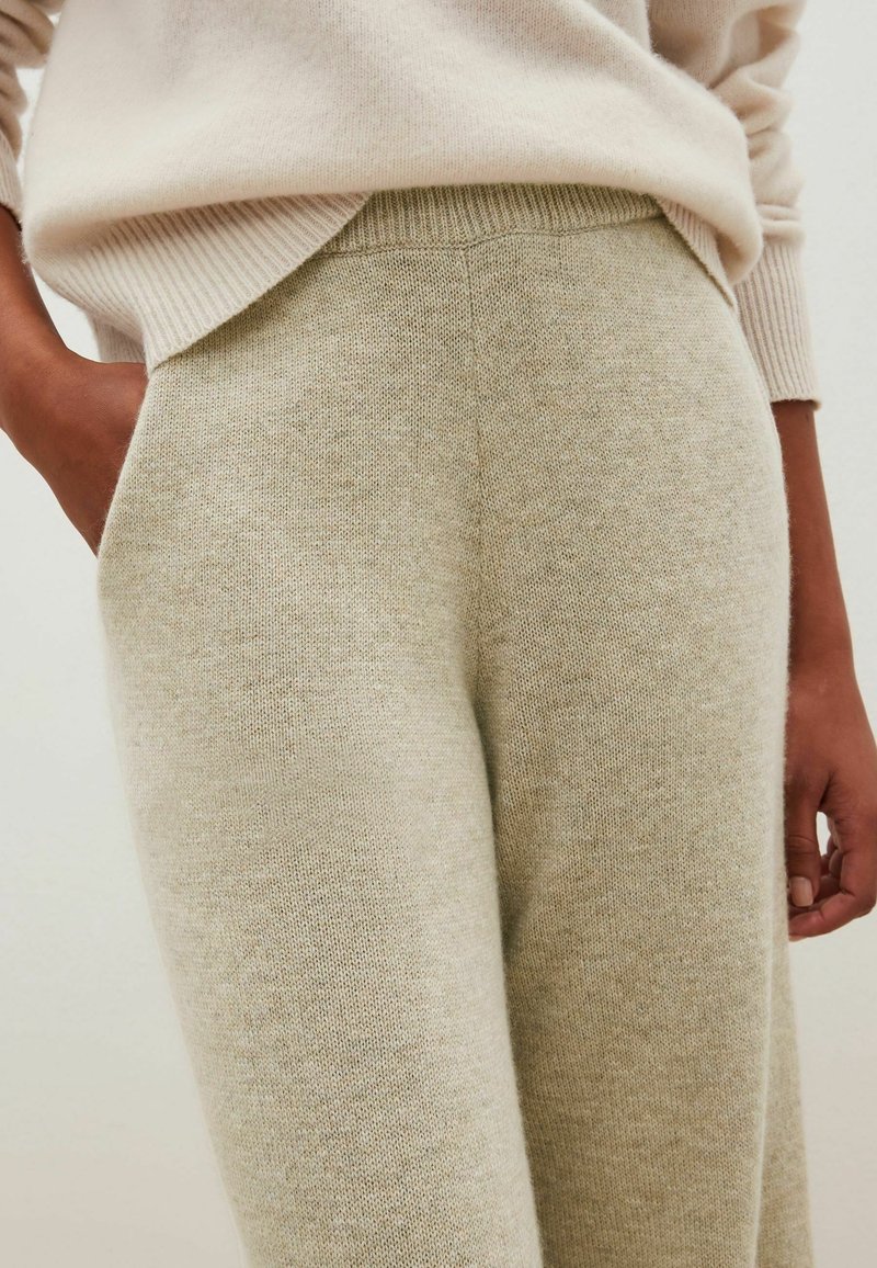 Licht beige gebreide broek met een zachte textuur, met een recht model en zakken, gecombineerd met een bijpassende licht beige trui.