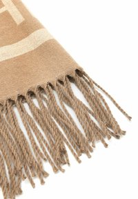 Beżowy, pleciony szal w kącie z skręconymi frędzlami na białym tle.