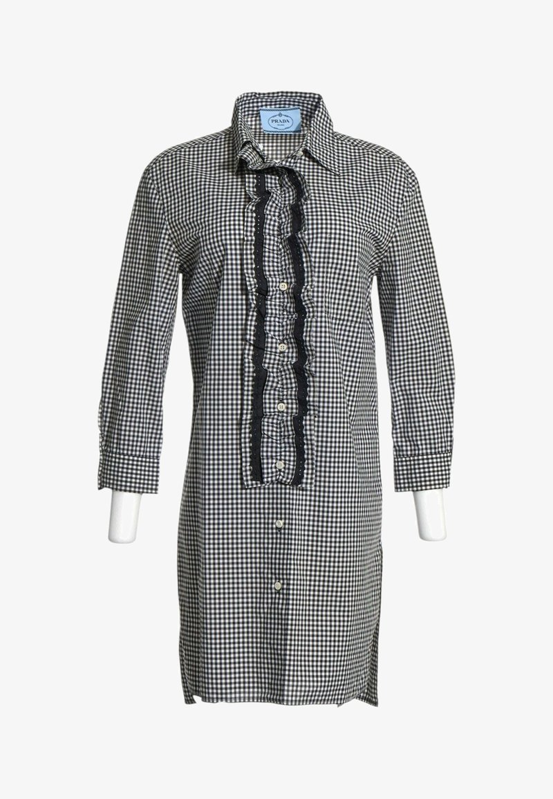 Chemise à manches longues à carreaux noir et blanc avec patte de boutonnage à volants et col, présentée sur un buste de mannequin.