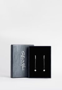 Silverhänge i droppform med cirkulära kristallaccent, presenterade i en texturerad svart och silverbox. Kedjelängderna varierar, vilket säkerställer en elegant design.