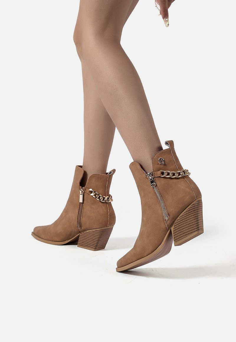Stivaletti alla caviglia in suede beige con zip laterale, dettaglio a catena e tacco squadrato con texture rigata. Design a punta.