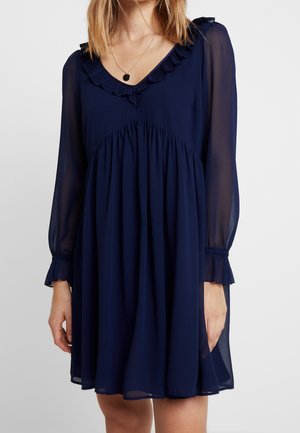 Navy blue dress with a V-neck, ruffled neckline, and long sheer sleeves. Features an elastic waistband and a flowing, flared skirt.
