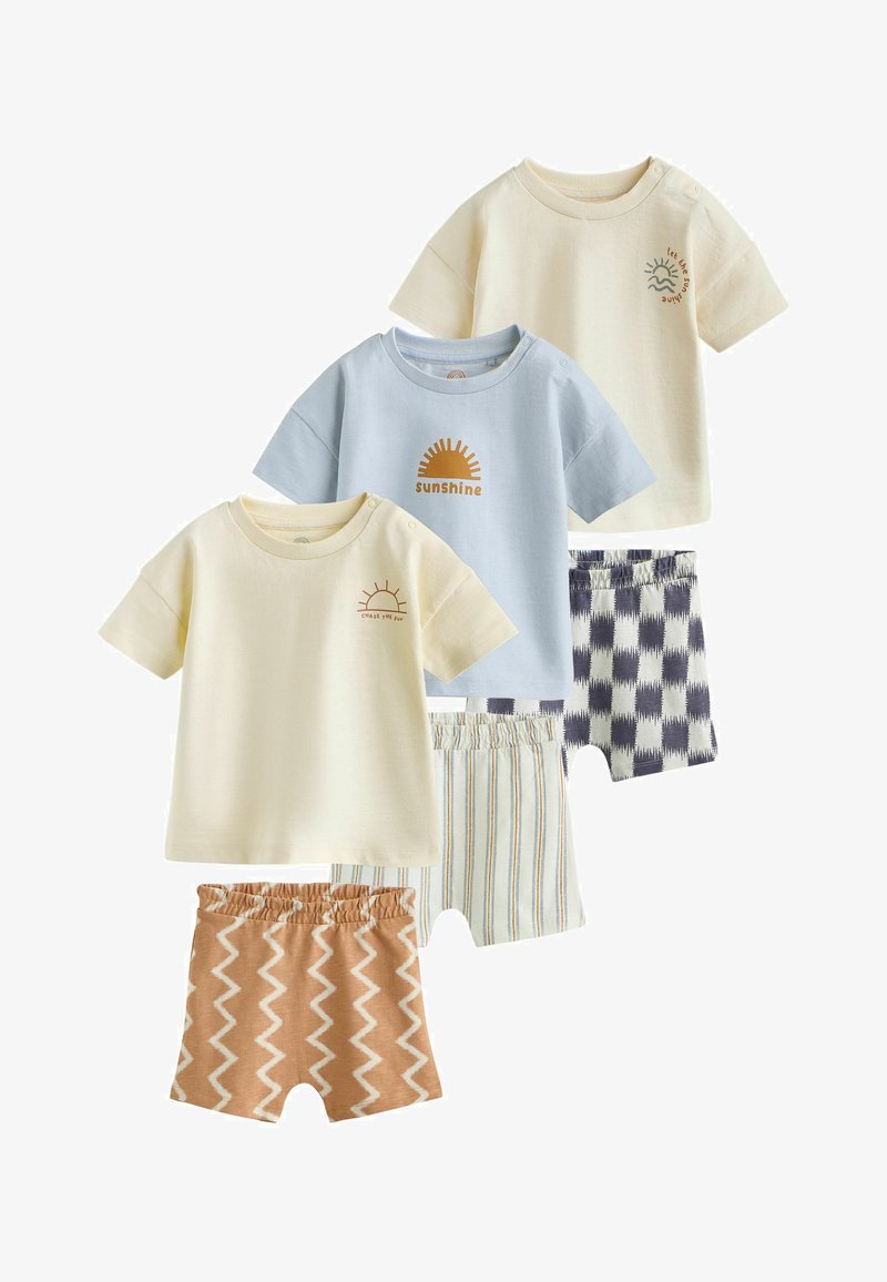 Trois tenues pour tout-petits avec des hauts à manches courtes en crème et bleu clair et des shorts assortis à motifs zigzag, rayures et carreaux.