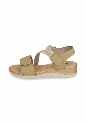 Sandalo beige con punta aperta, cinturini regolabili, borchie decorative sulla fascia anteriore, bande elastiche e suola a zeppa bassa per una calzata confortevole.