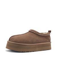 Scarpa slip-on in suede marrone con suola spessa e texturizzata, cuciture decorative e un accento a motivo lungo il colletto.