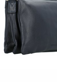 Borsa a tracolla in pelle nera texture, con doppie tasche e un passante per la tracolla cucito visibile di lato.