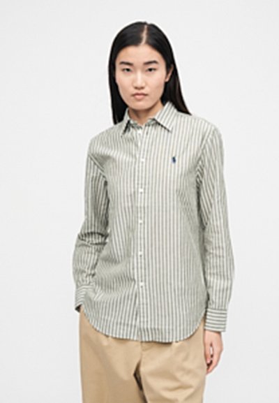 Cămașă cu nasturi cu dungi verzi și albe, cu guler, mâneci lungi și tiv rotunjit. Are un logo mic albastru pe piept.