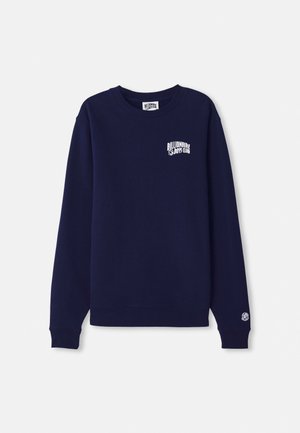 Sweatshirt bleu marine à col rond en coton avec un petit logo blanc sur la poitrine et un écusson logo sur le poignet. Coupe classique, ourlet côtelé.