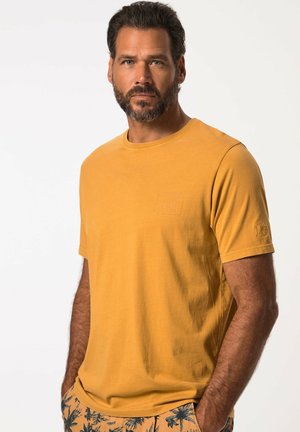 Gul bomulds t-shirt med korte ærmer, rund halsudskæring og et lille præget logo på brystet. Glat tekstur, afslappet pasform.