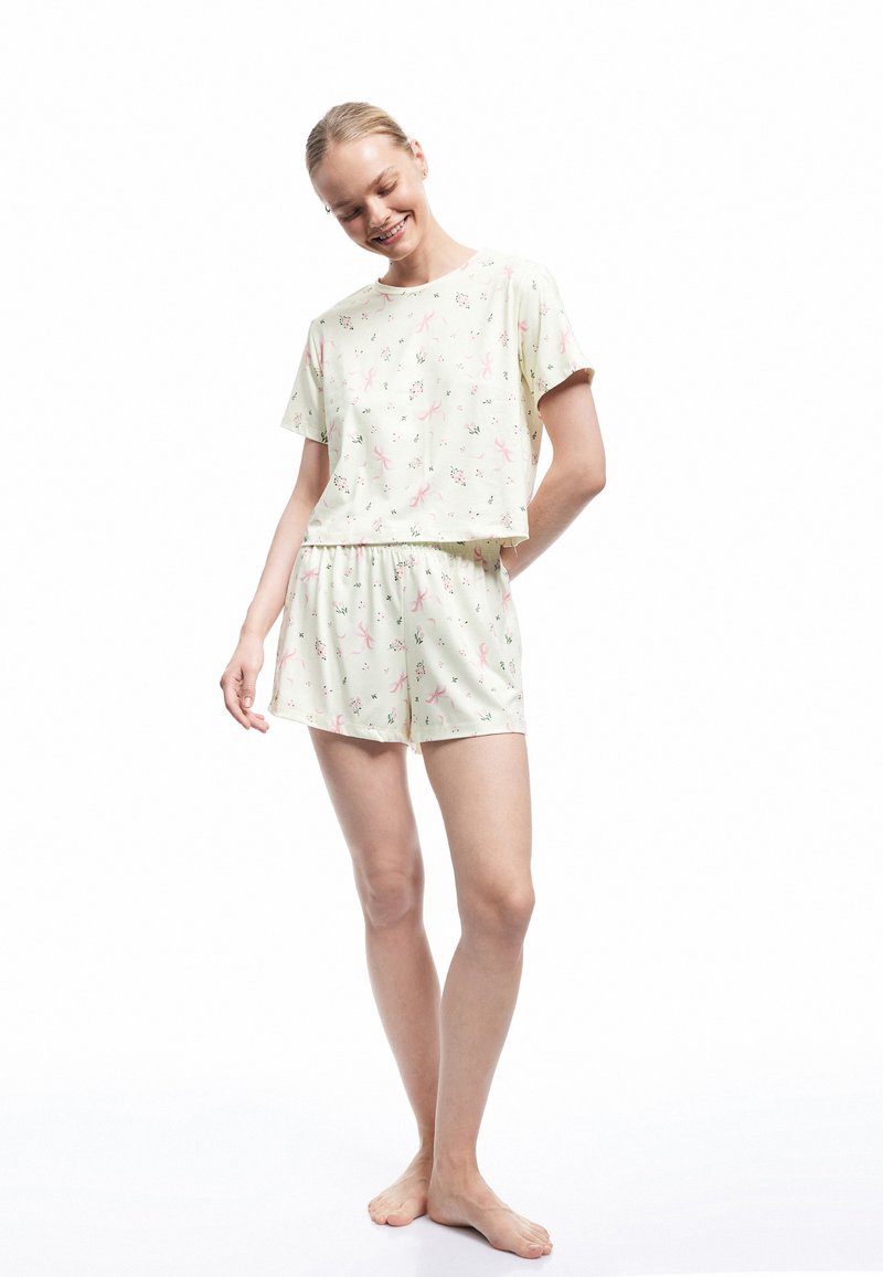 Kurzärmliges, kurzes Schlafanzugset aus lichtgrünem Stoff mit Blumen- und Bandmustern. Elastischer Bund an den Shorts. Weiches Textil.