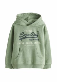Sudadera con capucha verde con un bolsillo frontal, que presenta un texto en estilo vintage en color navy que dice "SuperDry" y otros detalles de marca. Material de algodón.